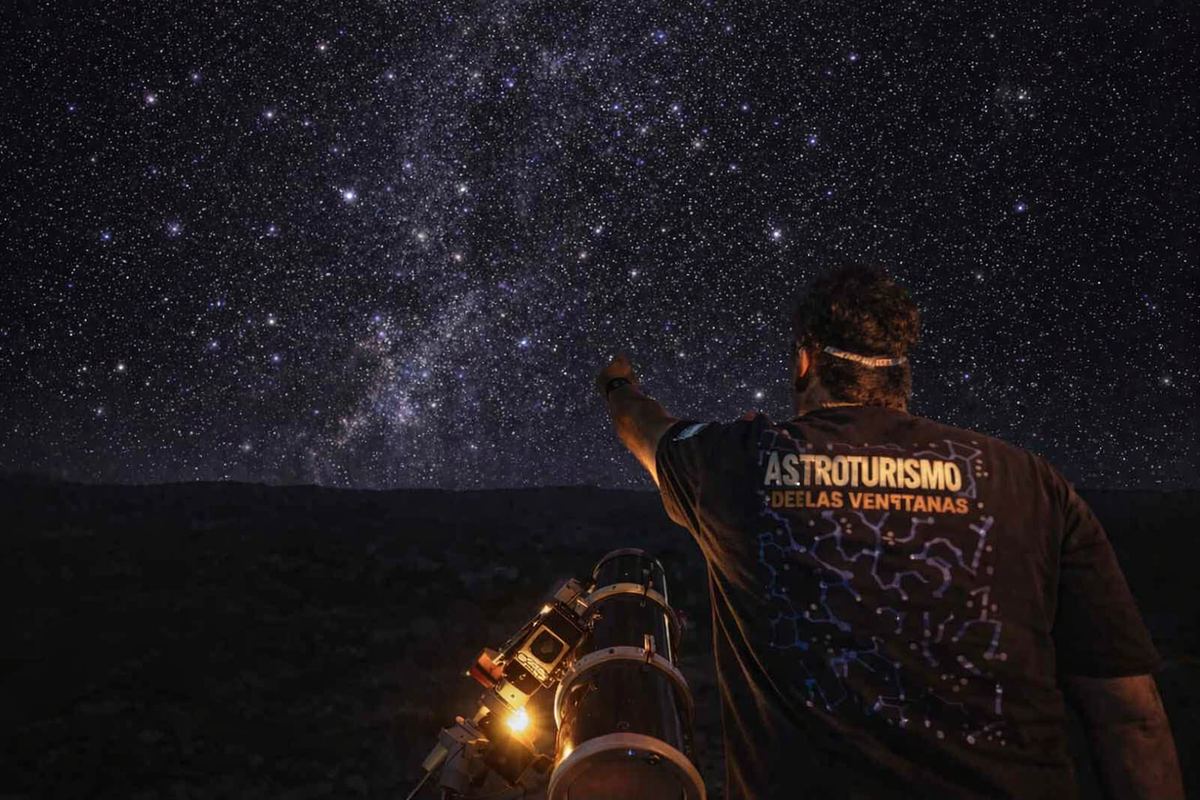 Gu&iacute;a se&ntilde;alando el cielo estrellado durante una salida de astroturismo