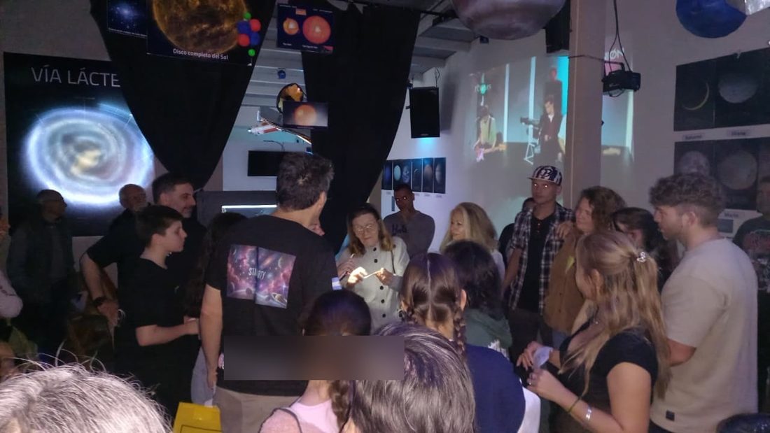 Grupo de visitantes en la sala principal de la exposici&oacute;n, con una pantalla de la V&iacute;a L&aacute;ctea