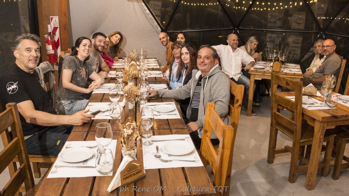 Grupo cenando pizzas en una mesa larga dentro del domo restaurante de Puente Blanco