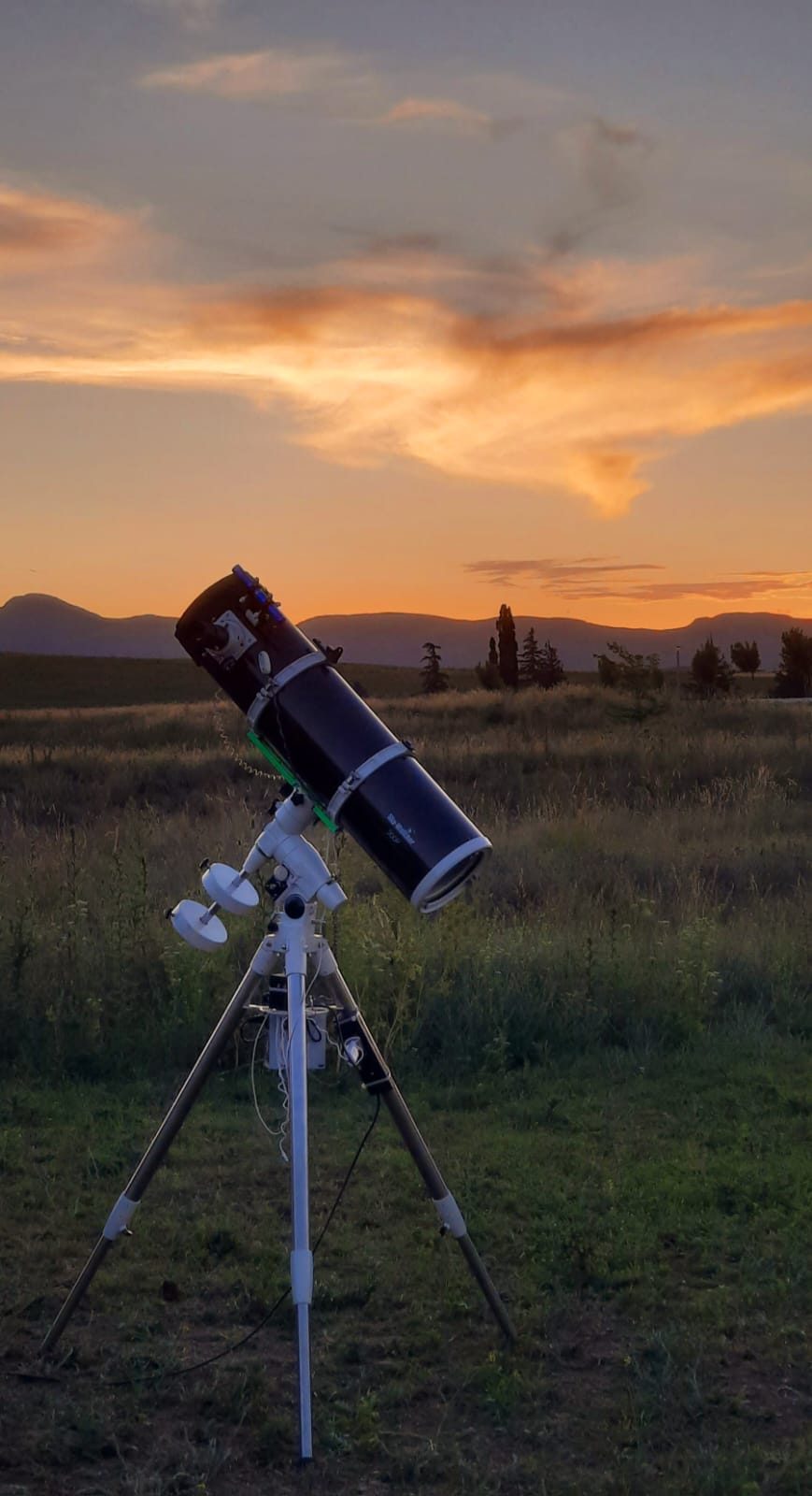 Guía explicando el cielo a un grupo sentado, con un telescopio al lado