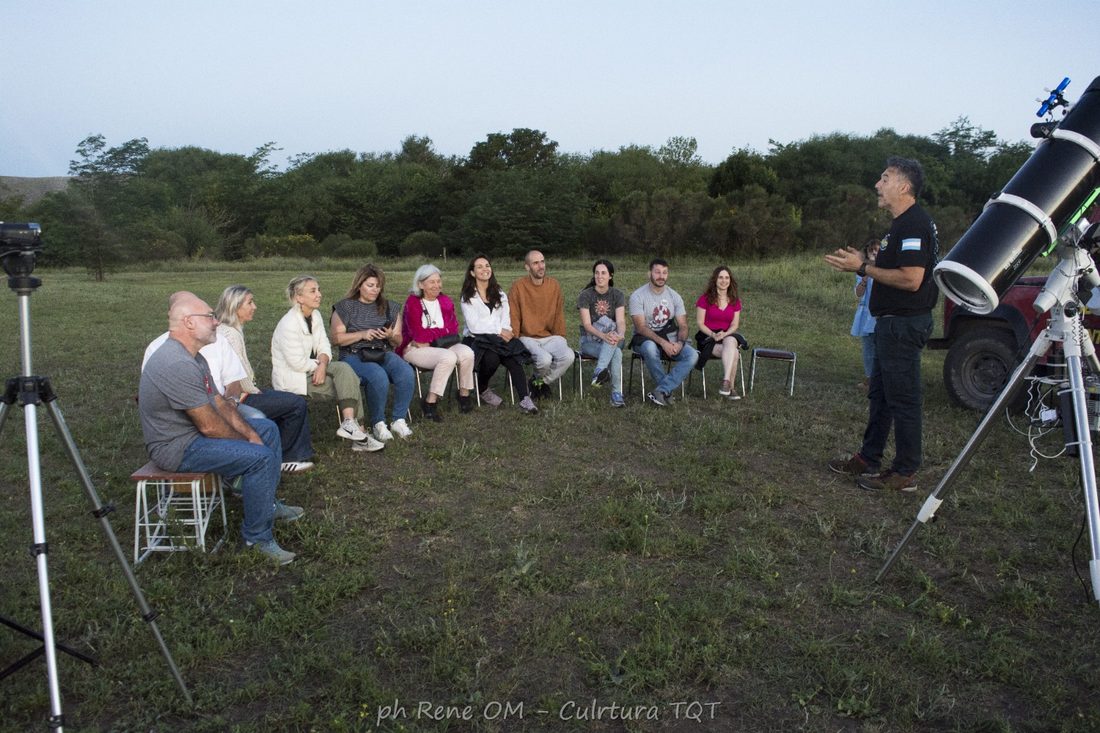 Grupo observando el cielo de espaldas, con la Luna visible sobre los domos