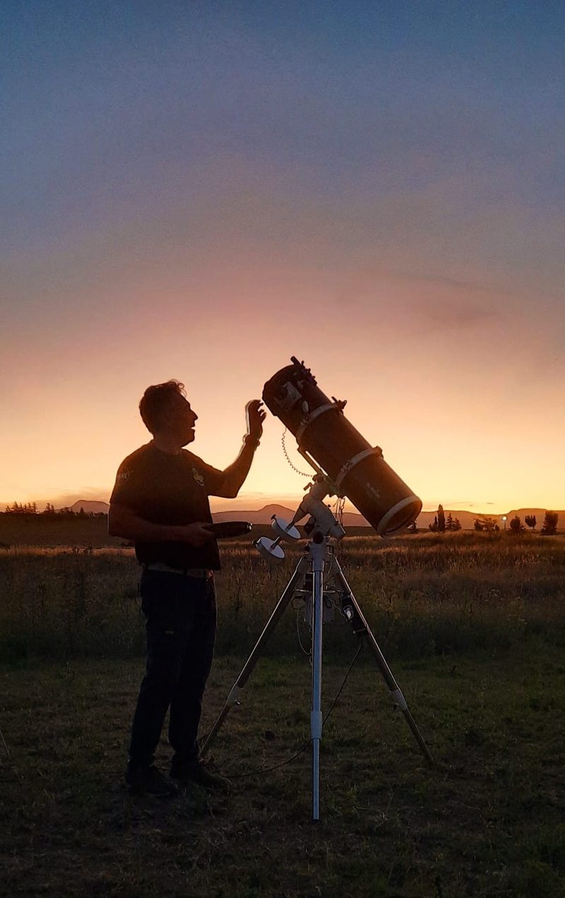 Gu&iacute;a ajustando un telescopio a contraluz, durante el atardecer